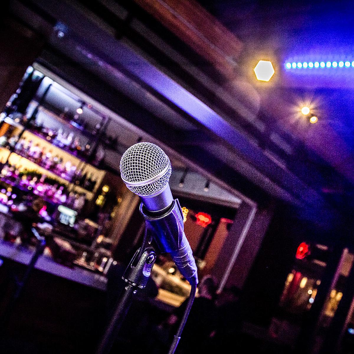Close up of a microphone. A bar with blue lighting is in the background.