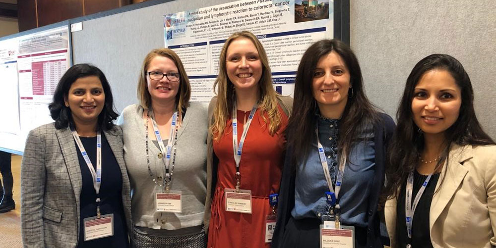 Some members of the the Ulrich Group standing in front of a research poster at a conference
