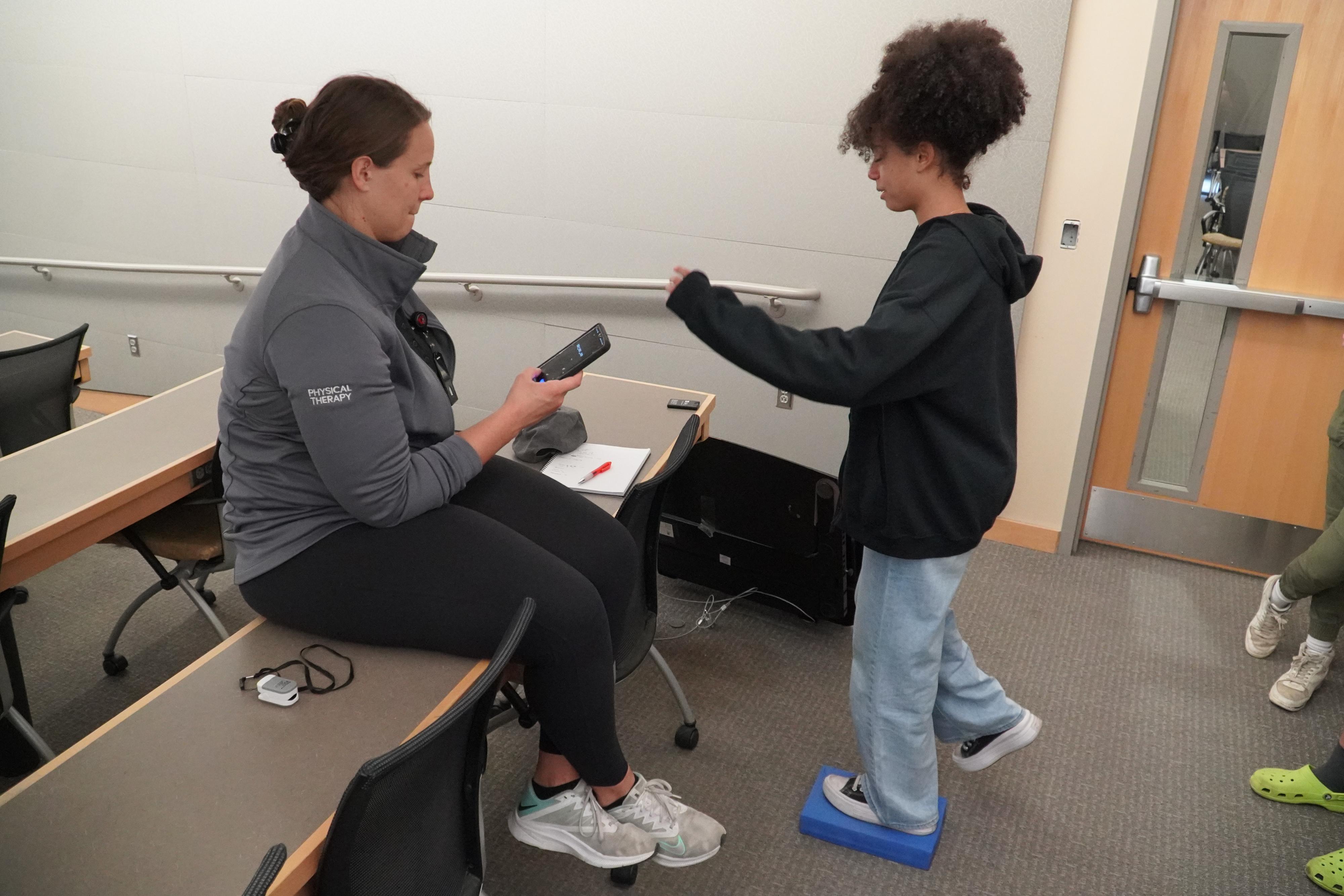a physical therapy mentor gives time to a student in a balancing activity at the Saturday Academy