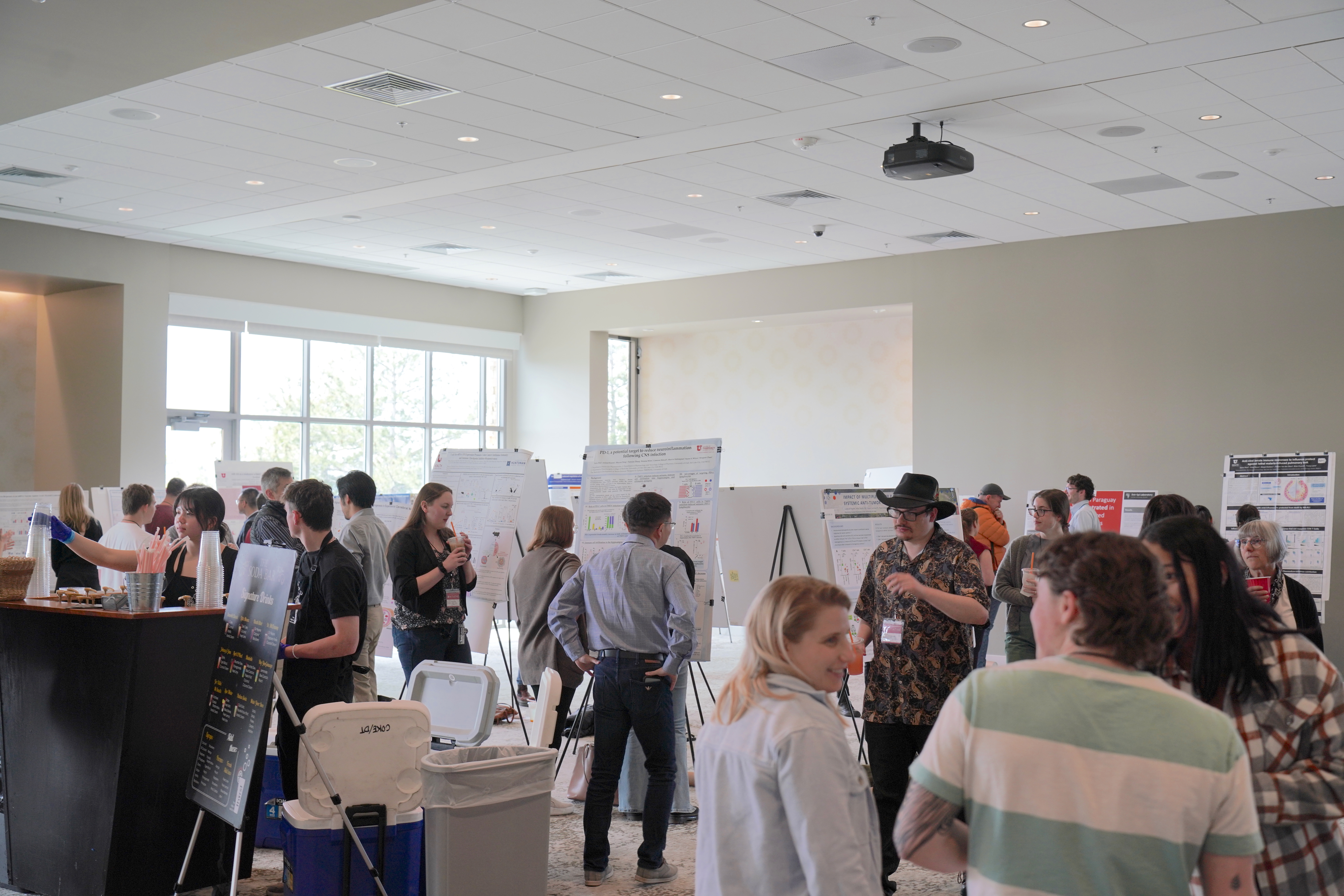 Scientists mingle and converse in a brightly-lit open poster forum.