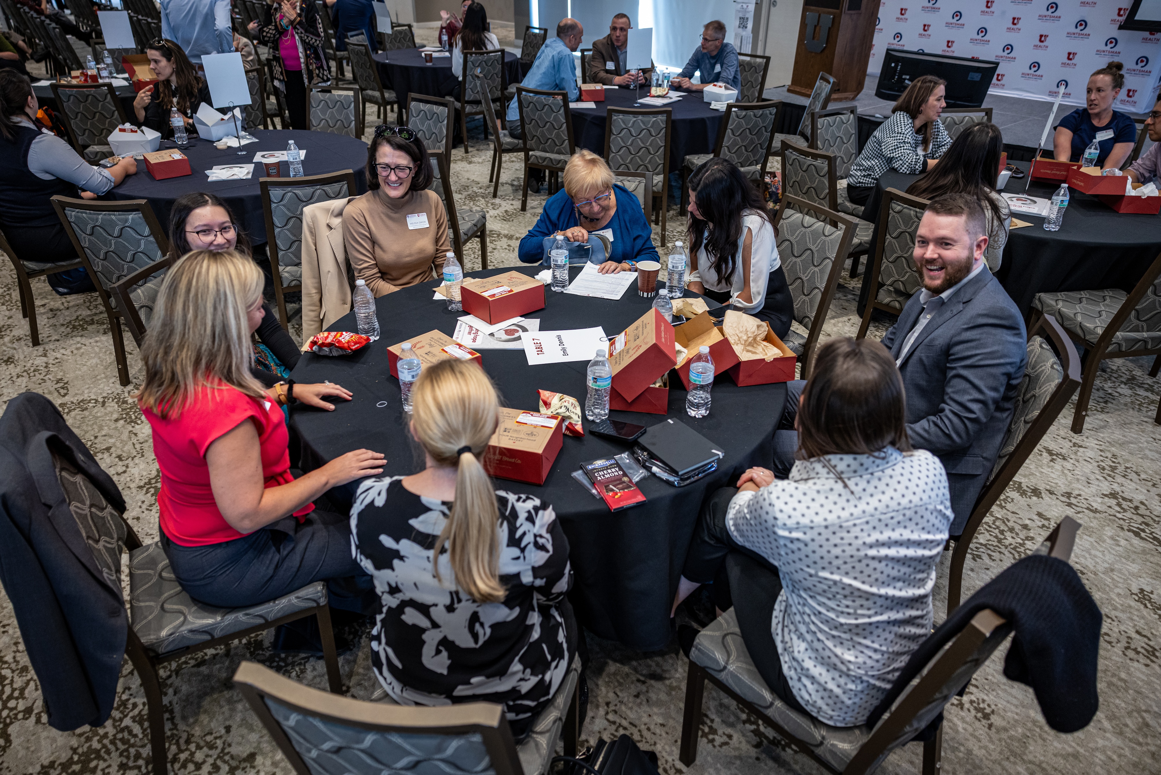 A group of researchers converses animatedly around a packed table. They look happy.