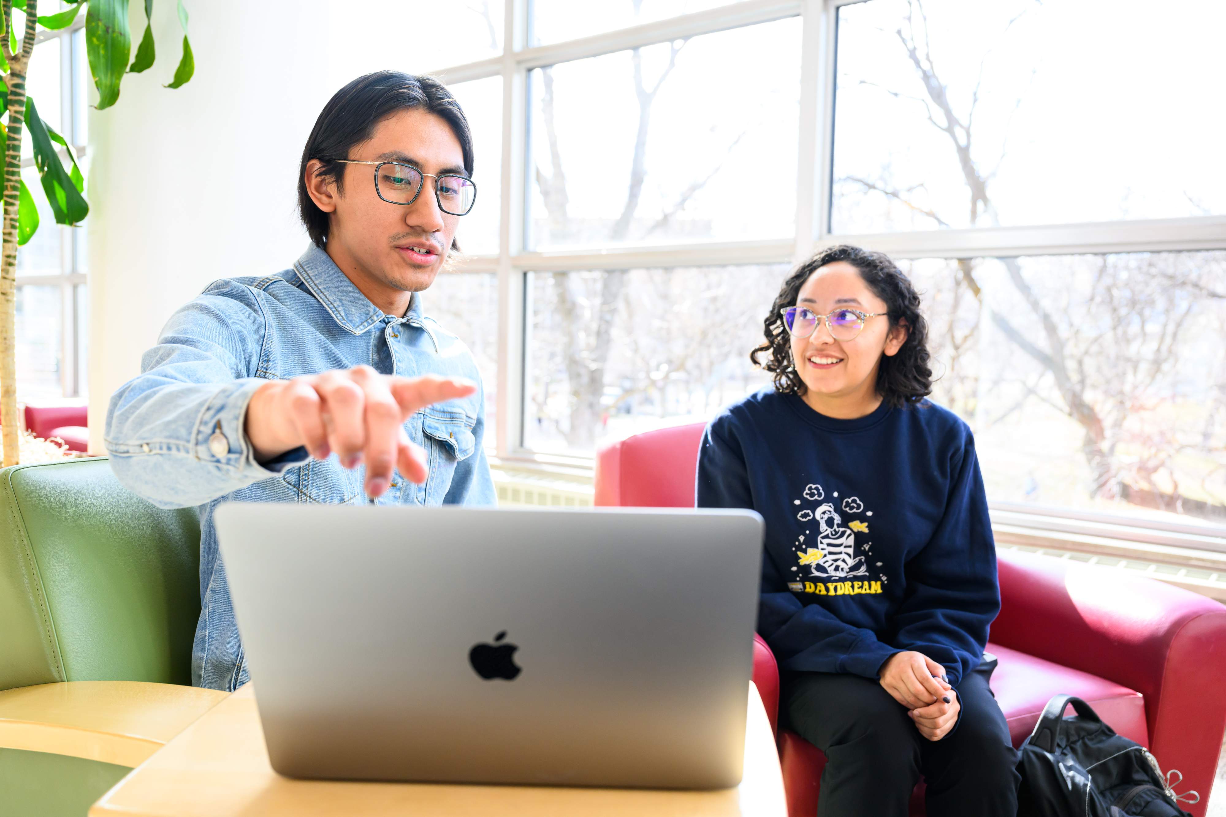 Two students in front of a laptop discussing.