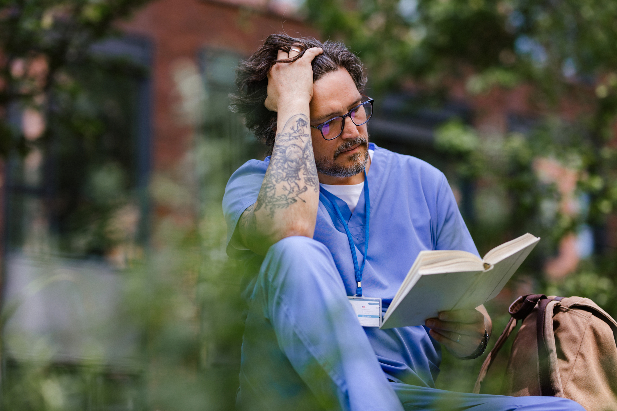 Person in scrubs reading outdoors