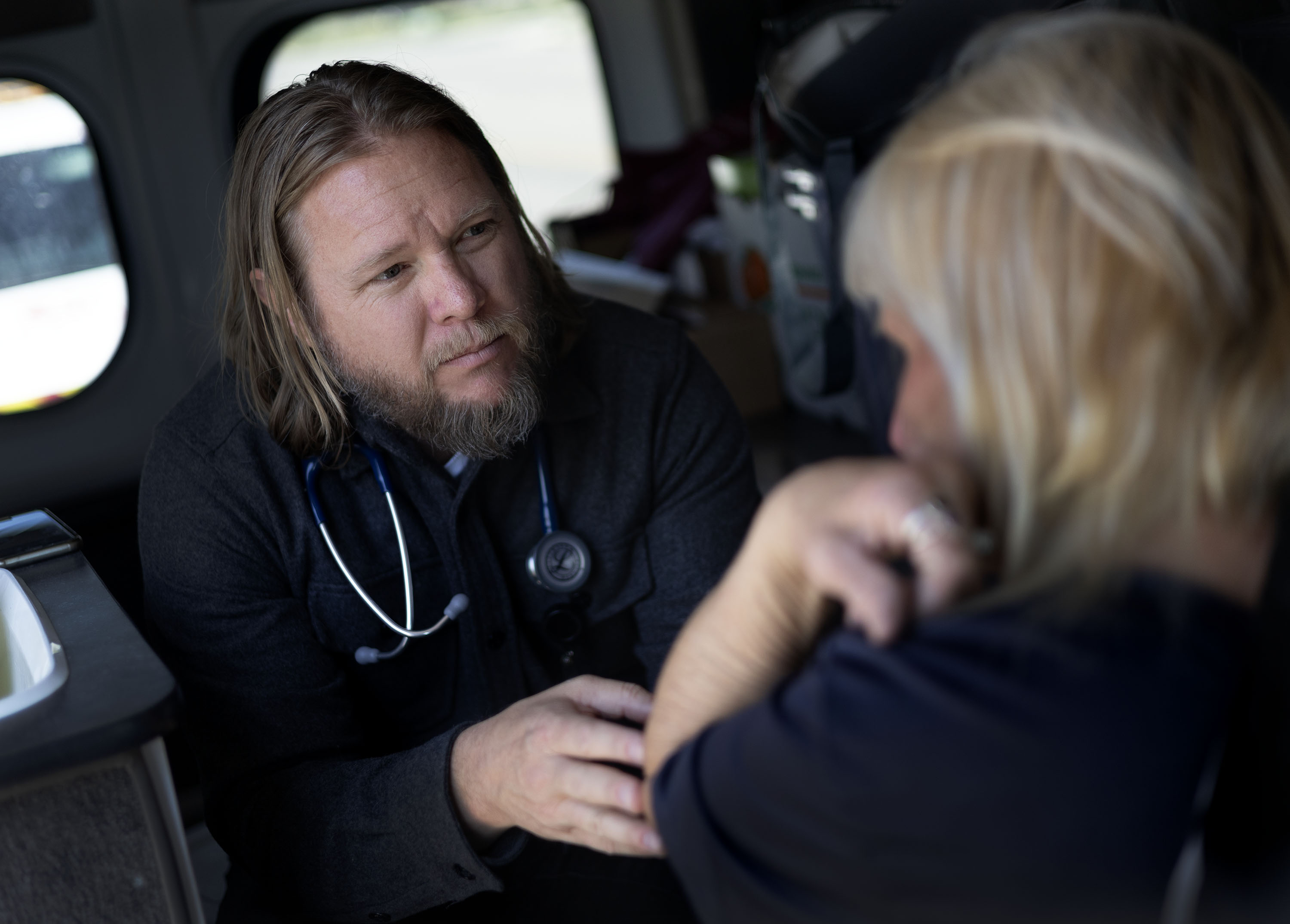Depending on each patient’s needs and preferences, Michael offers care either outside or in the mobile clinic. Here, he meets with a patient in the van—maintaining steady eye contact and full attention throughout the visit.
