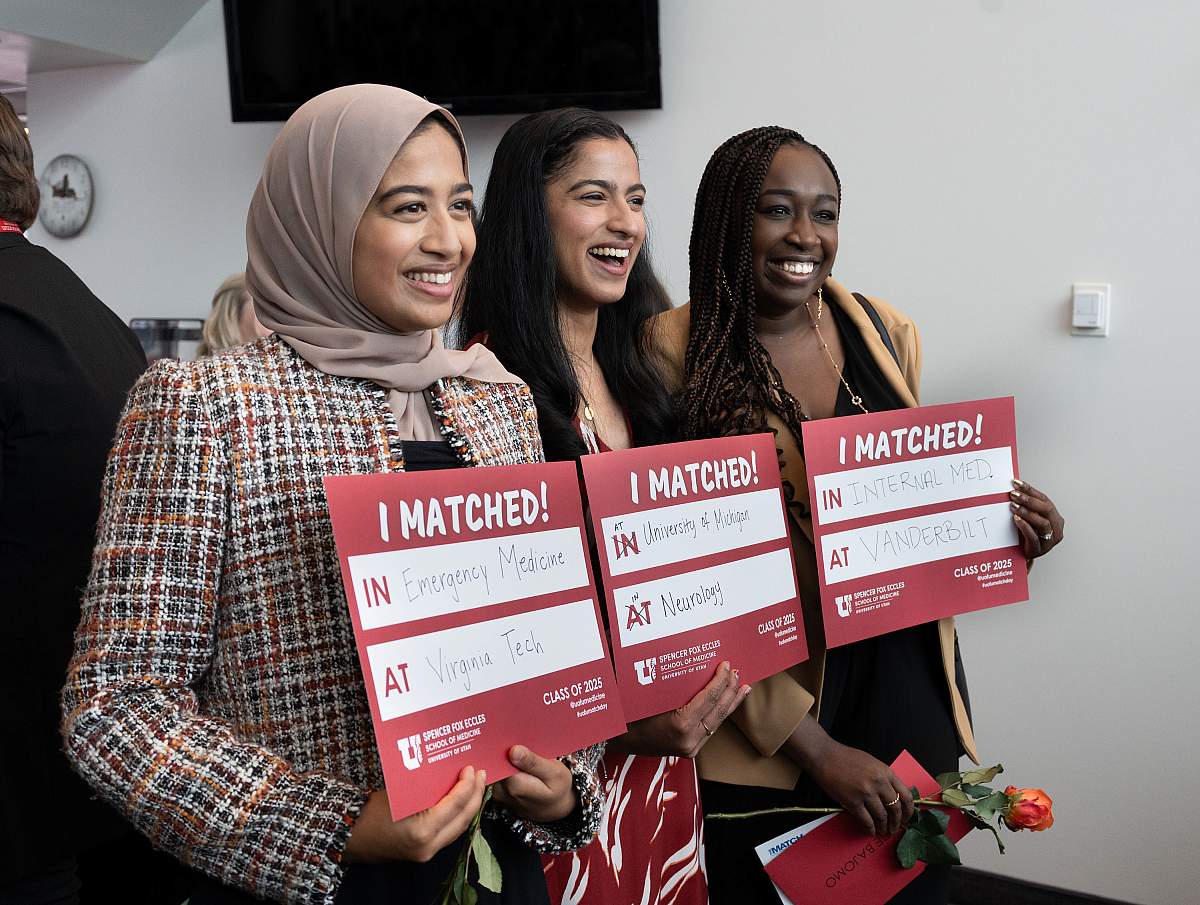 Three students hold up Match Day signs.