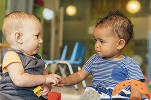 A caucasian and African American toddler interact.