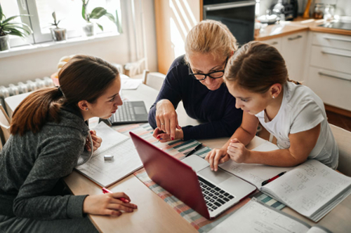 Mother helping her daughters with school work at home