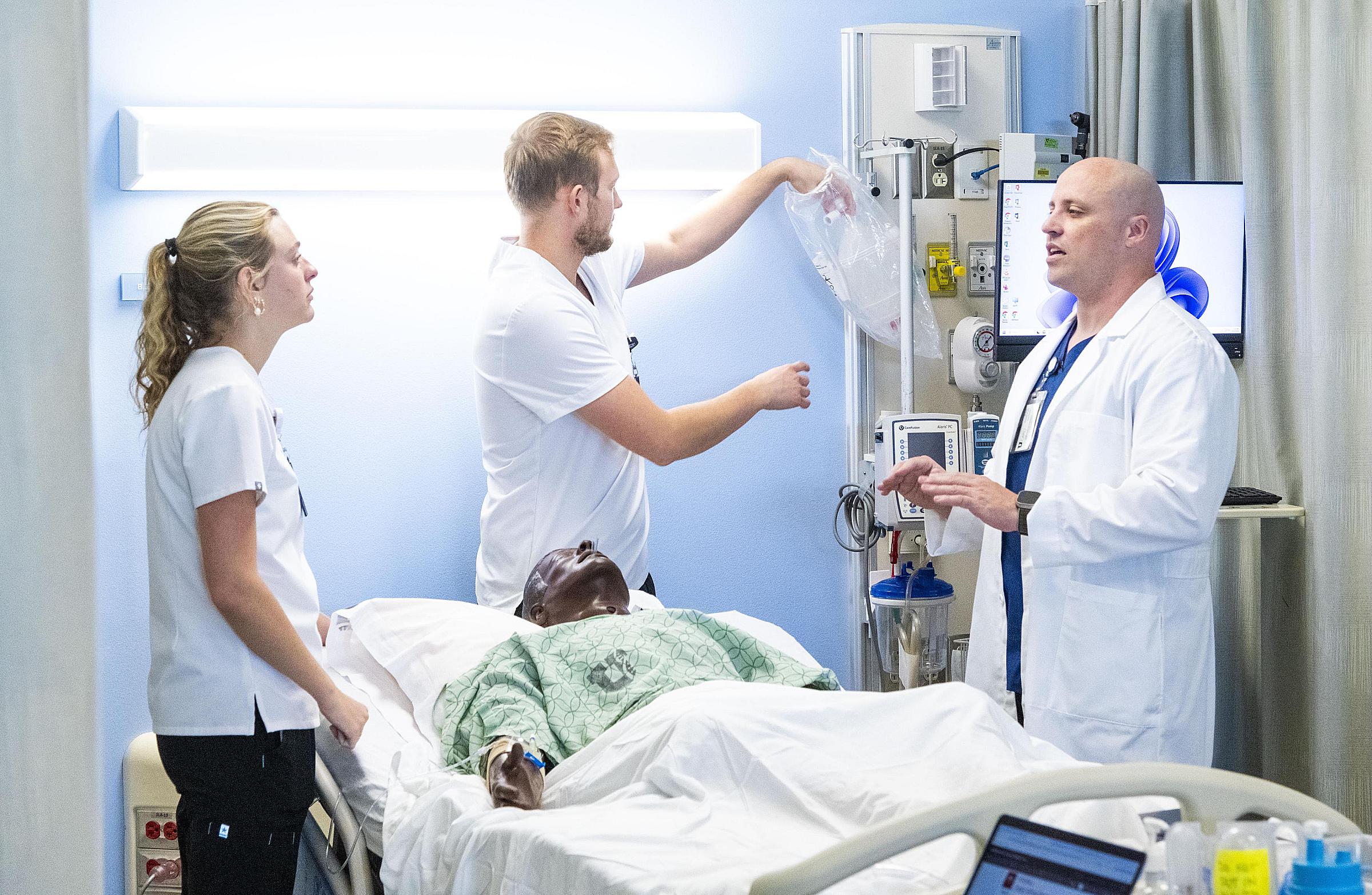 College of Nursing instructor Christopher Sneddon, RN-MSN, (right) with students in the simulation center. 