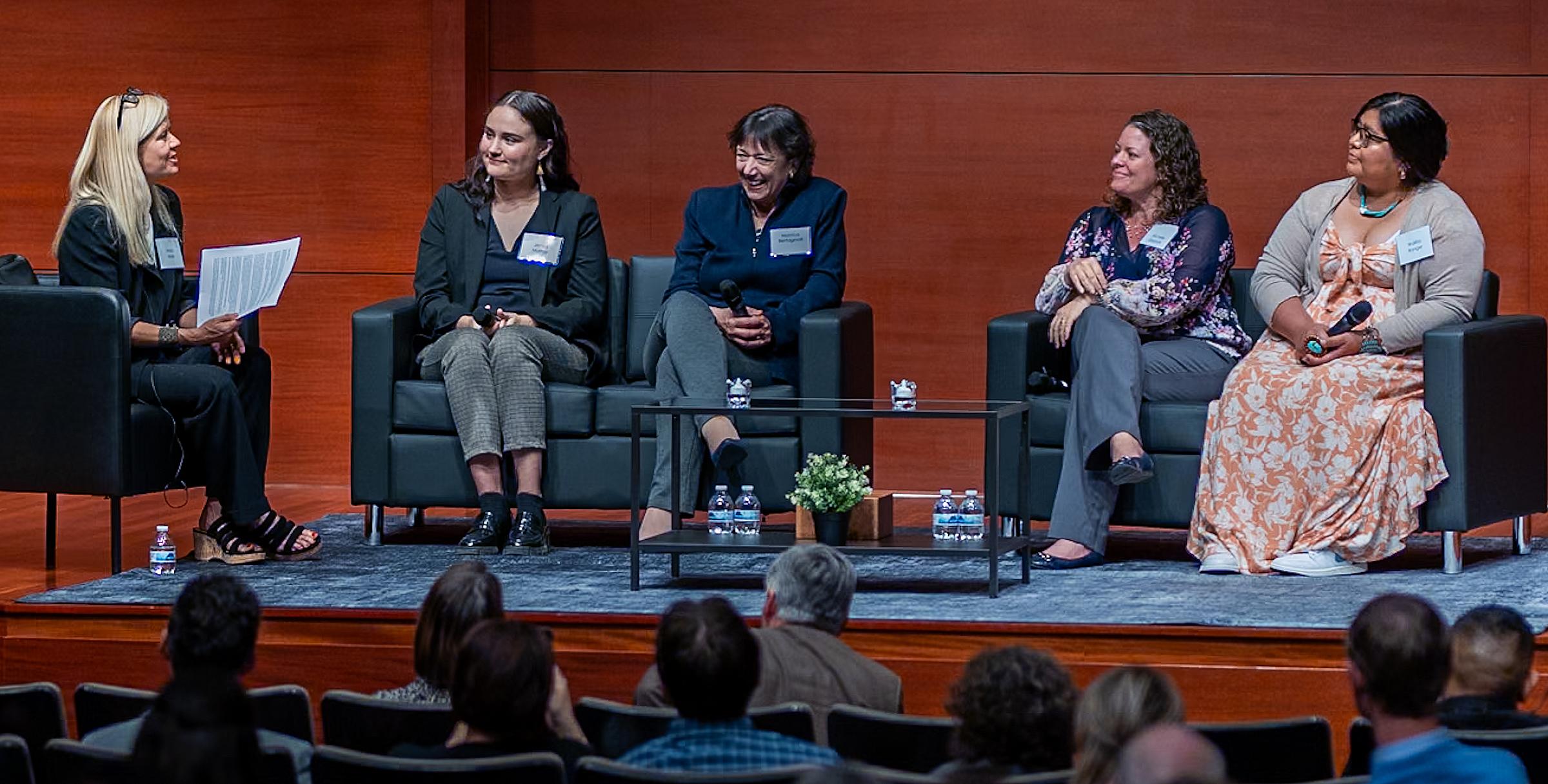 Five panelists in a discussion on a stage.