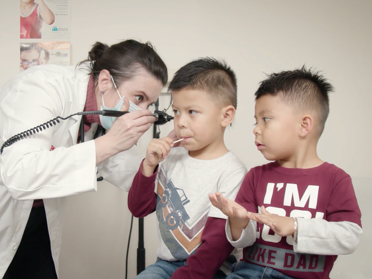 Student doctor examining children's ears, Midvale