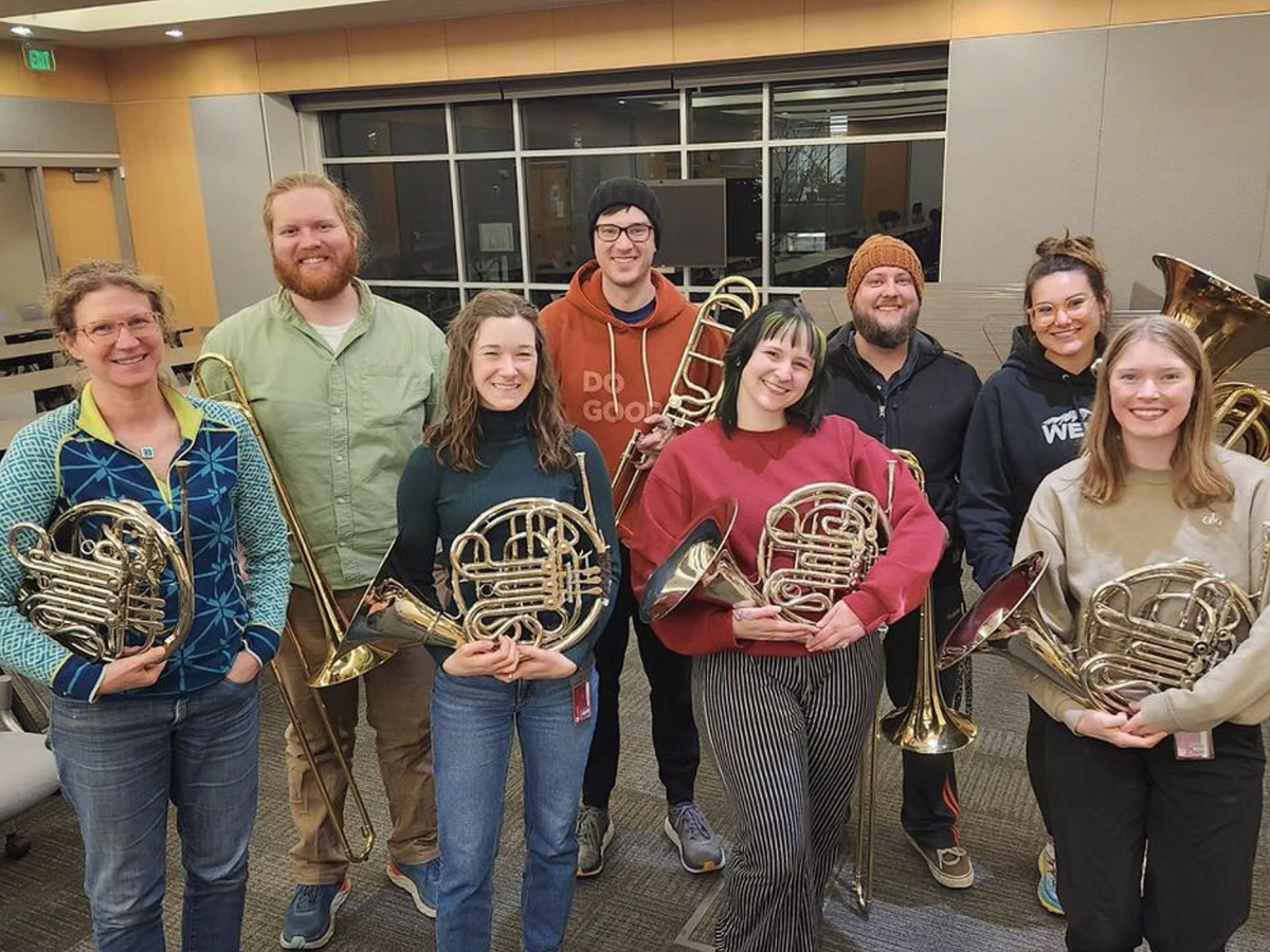 A group of french horn players standing together for a group photo.