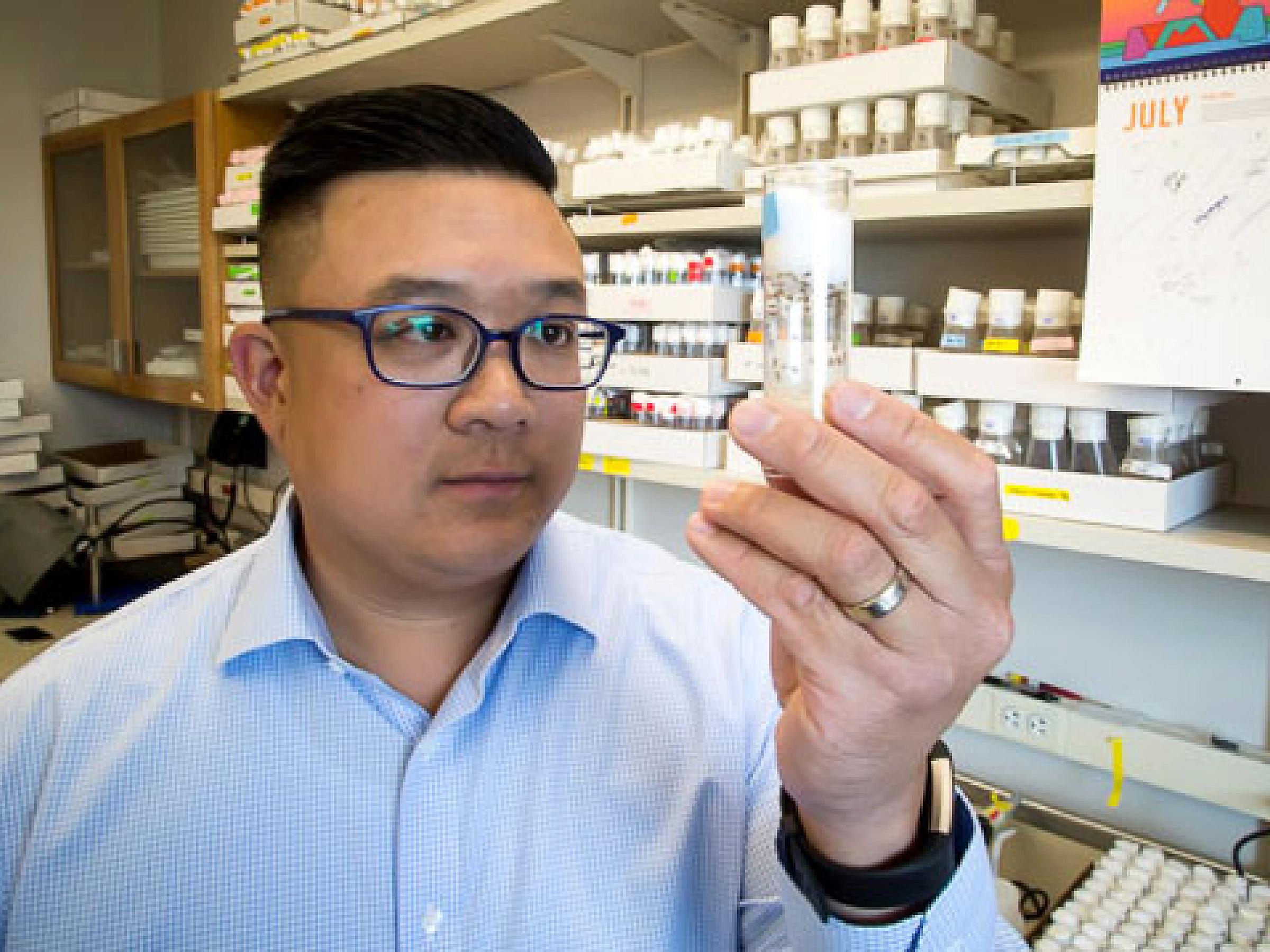 Clement Chow looking at a vial against a lab background