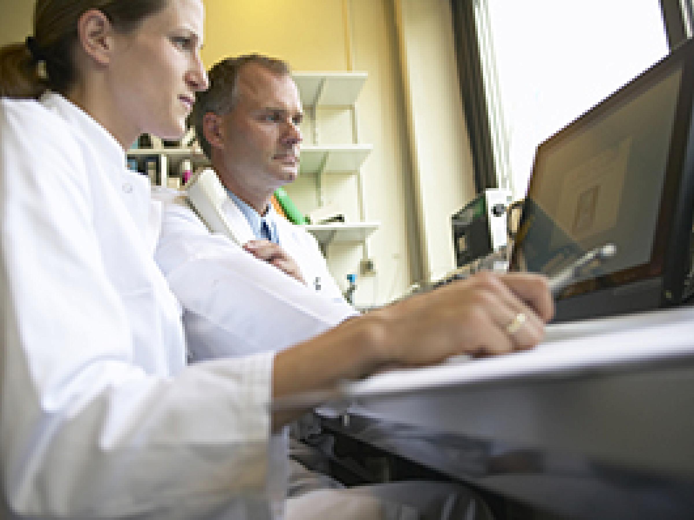 Two doctors sitting in front of a computer: New Tools to Mine Health Datasets May Uncover the Genetic Causes of Heart Defects