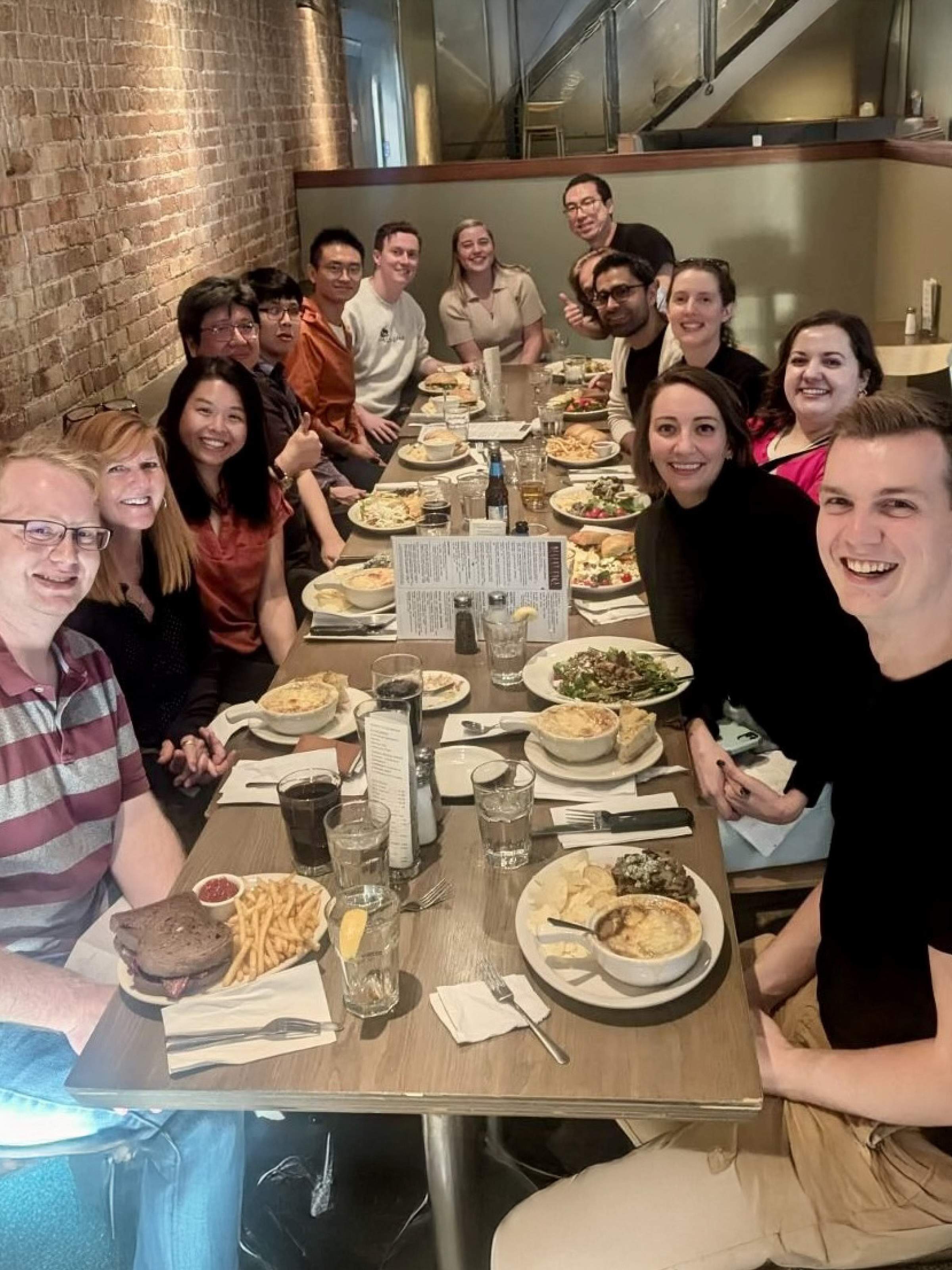 Young Lab members sitting at a long table at a restaurant