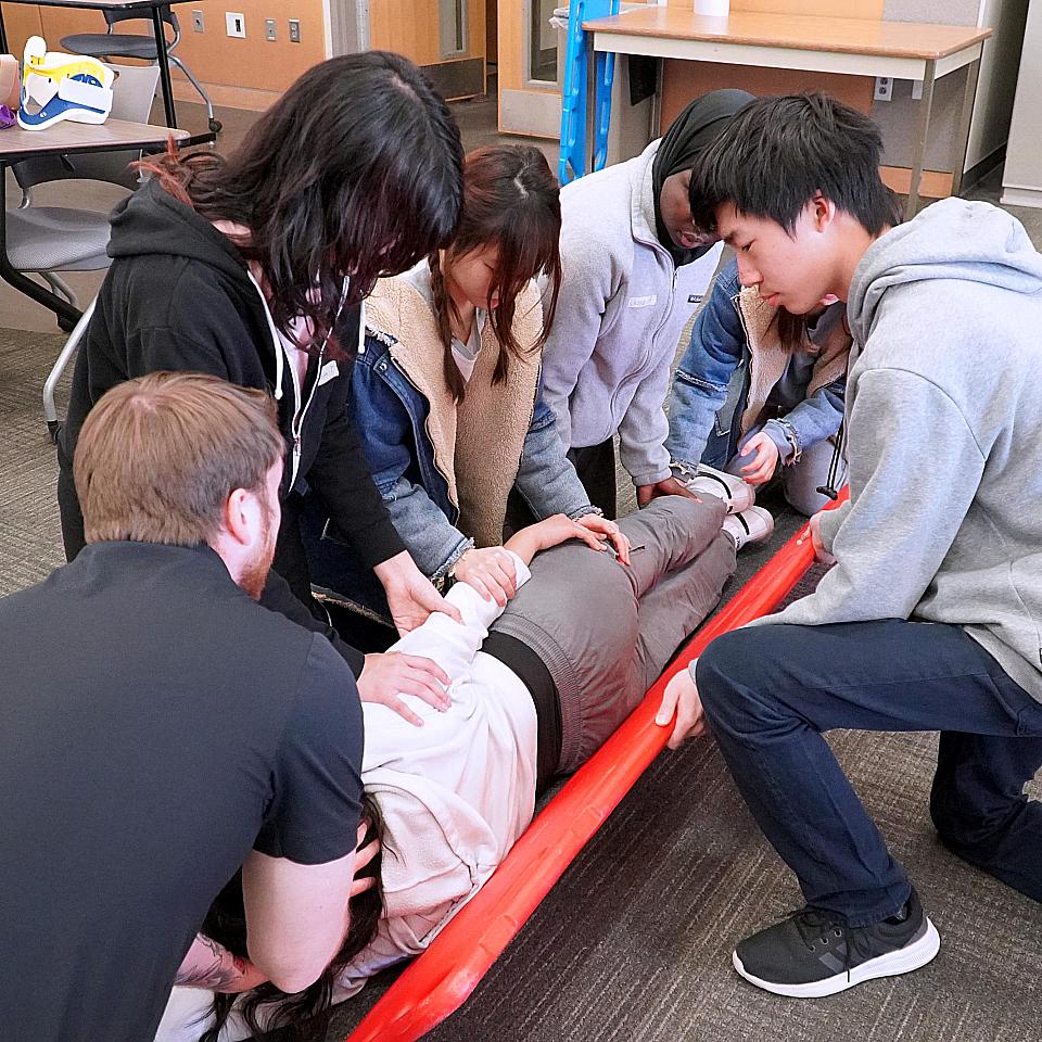 Saturday Academy students practice placing a person in a stretcher
