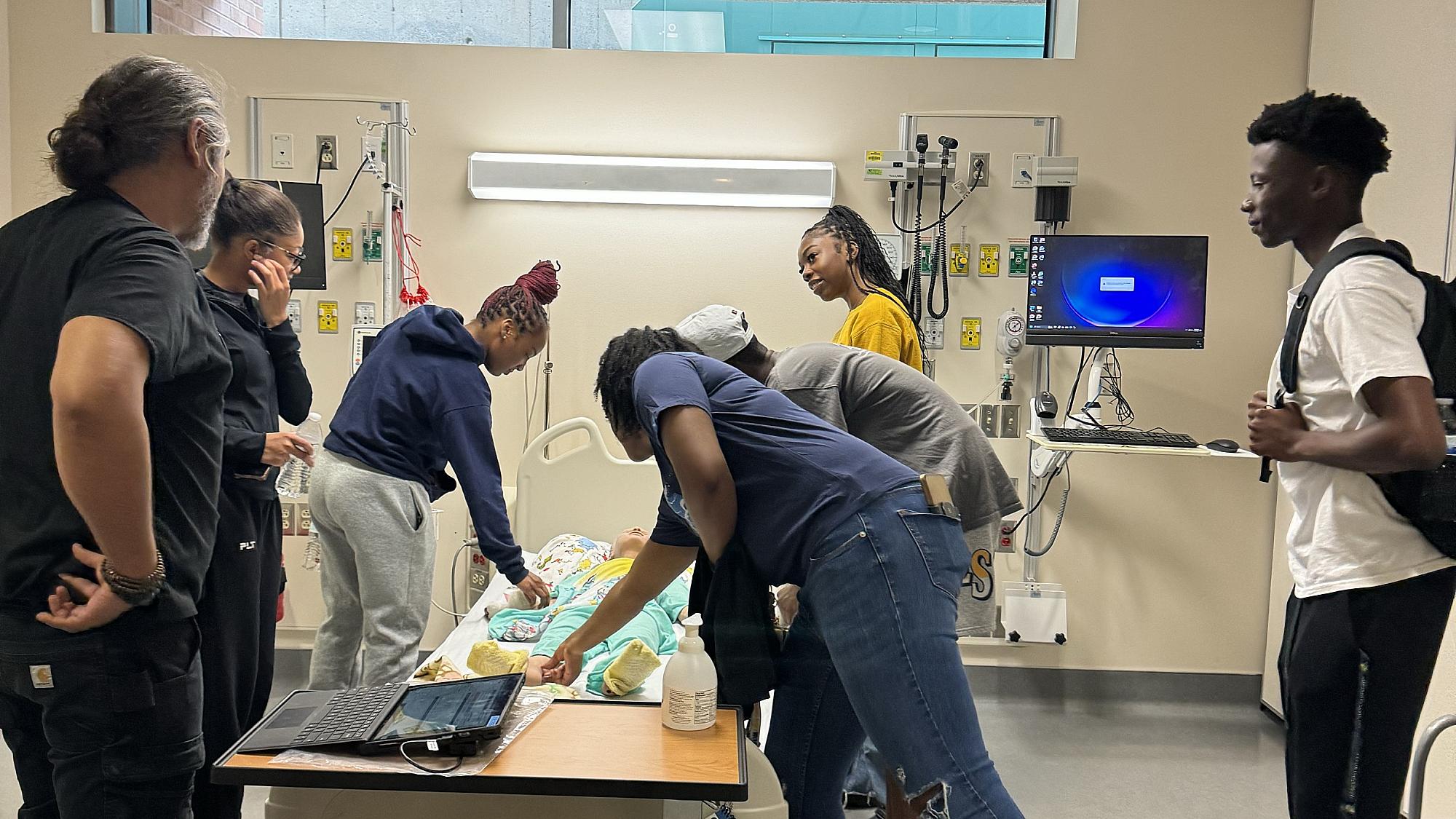 six students prepare a mannequin in the College of Nursing Simulation Center