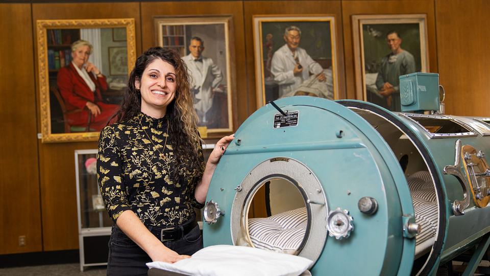 Donna Baluchi stands next to an iron lung machine at the Eccles Health Sciences Library