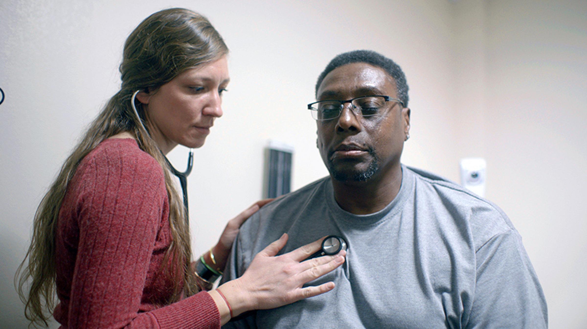 Provider checks man's heart beat with stethoscope