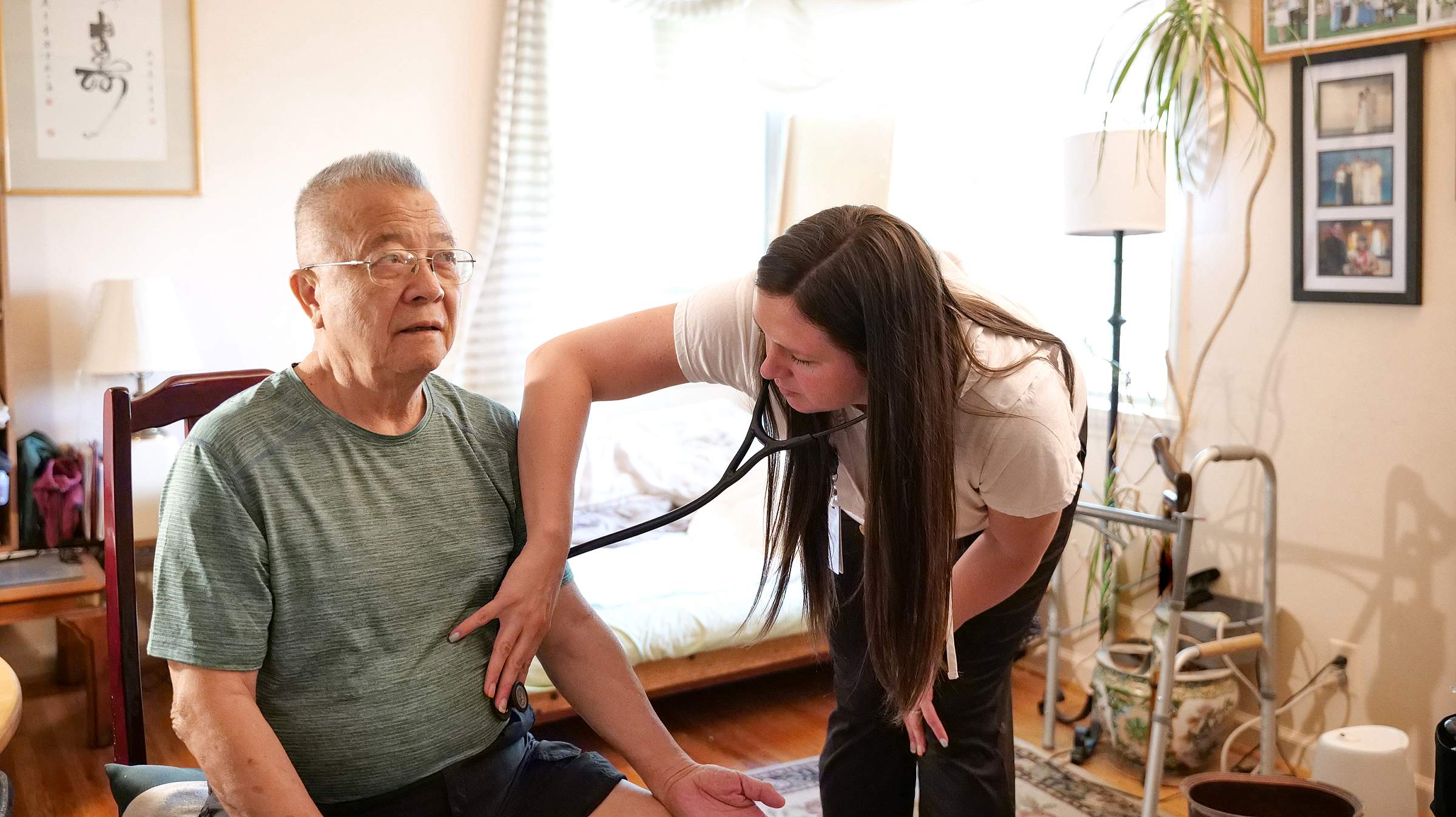 Nurse listens to patient's heart at their home