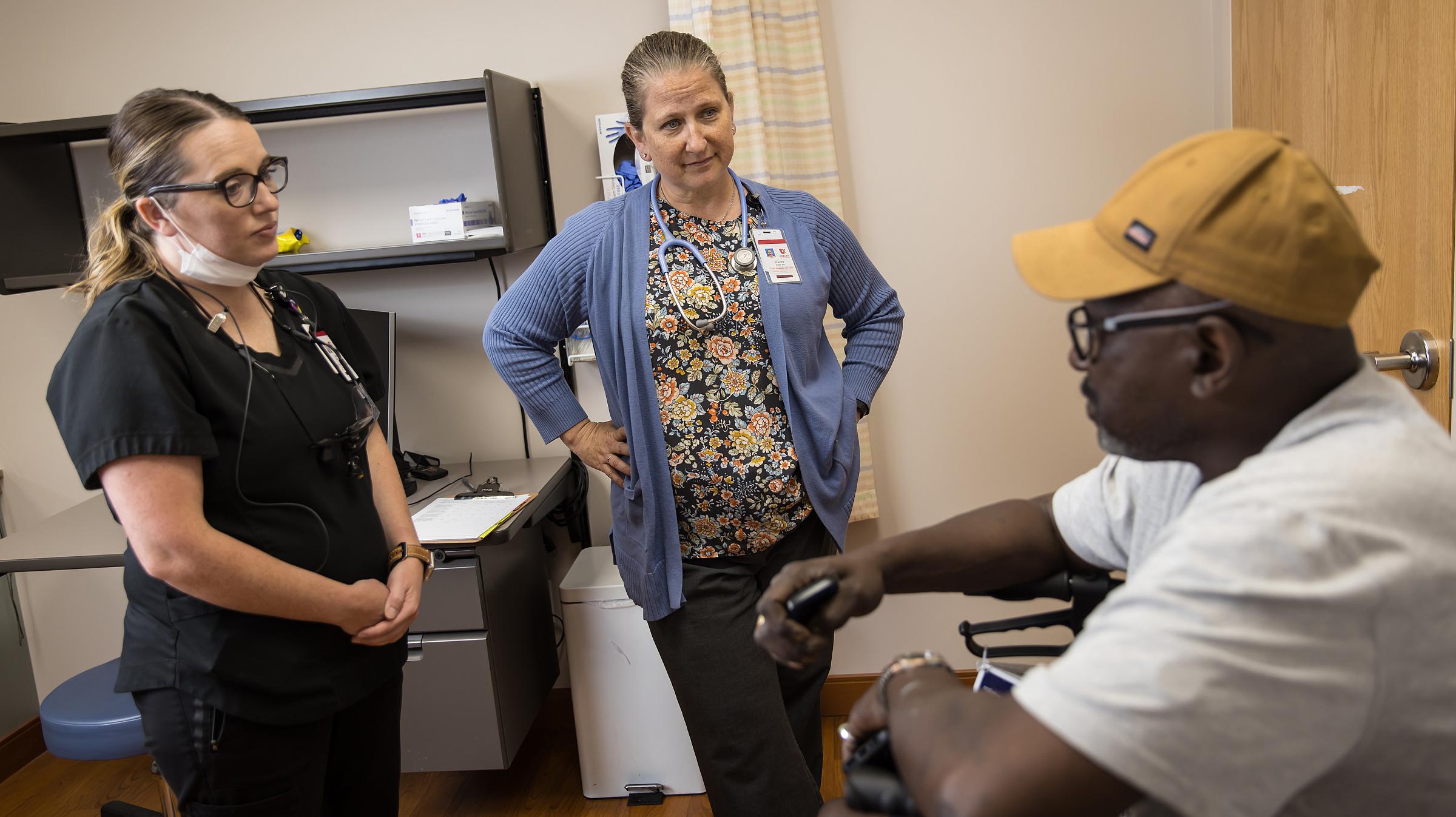 two providers consult with a patient in an exam room