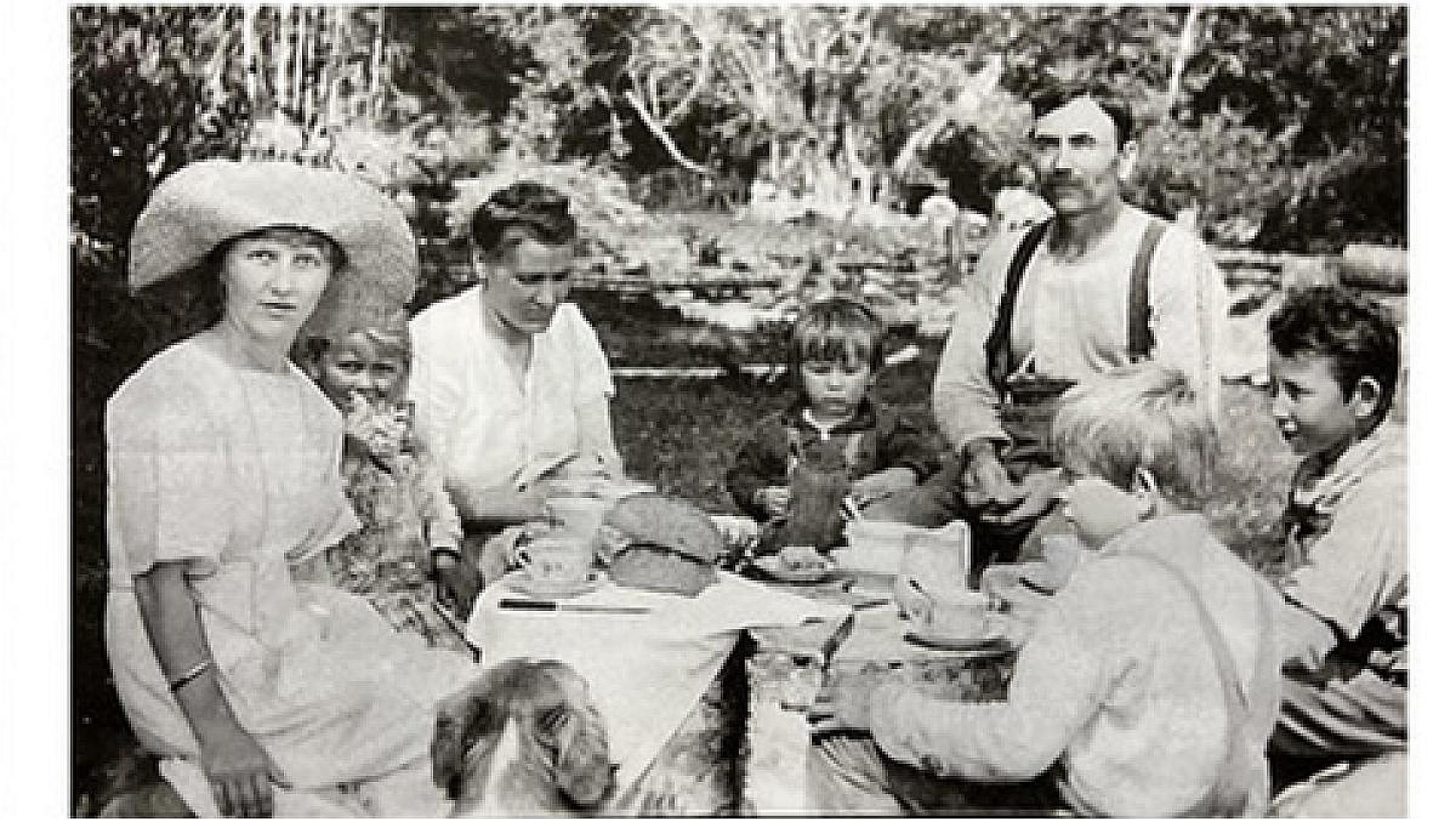 A vintage photo of a family eating outside.