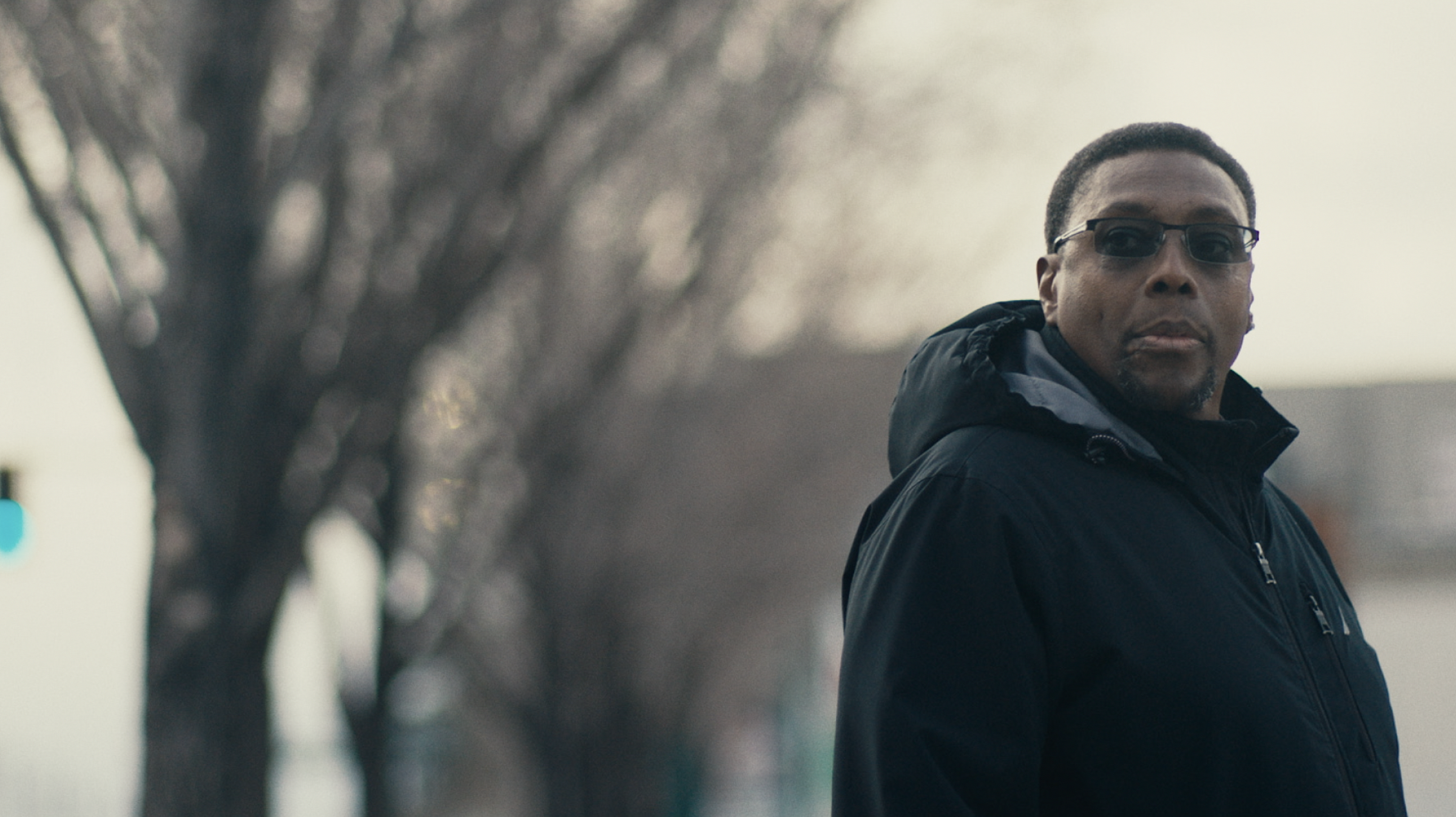 man stands in city looking towards camera