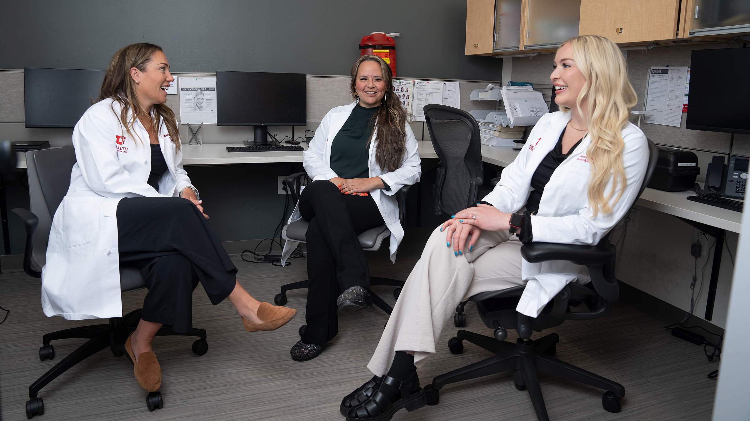 Three providers from the plastic surgery team sitting in office chairs having a conversation.