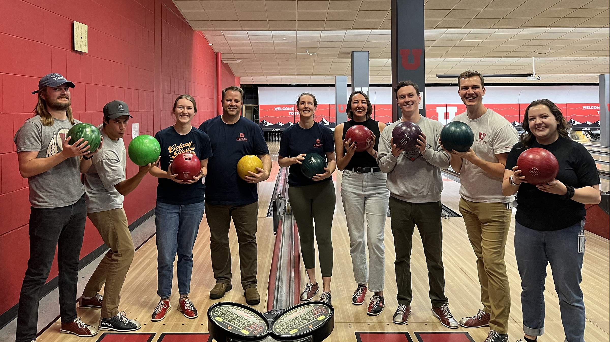 Young Lab and Williams Lab members holding up bowling balls while standing in front of the bowling lane