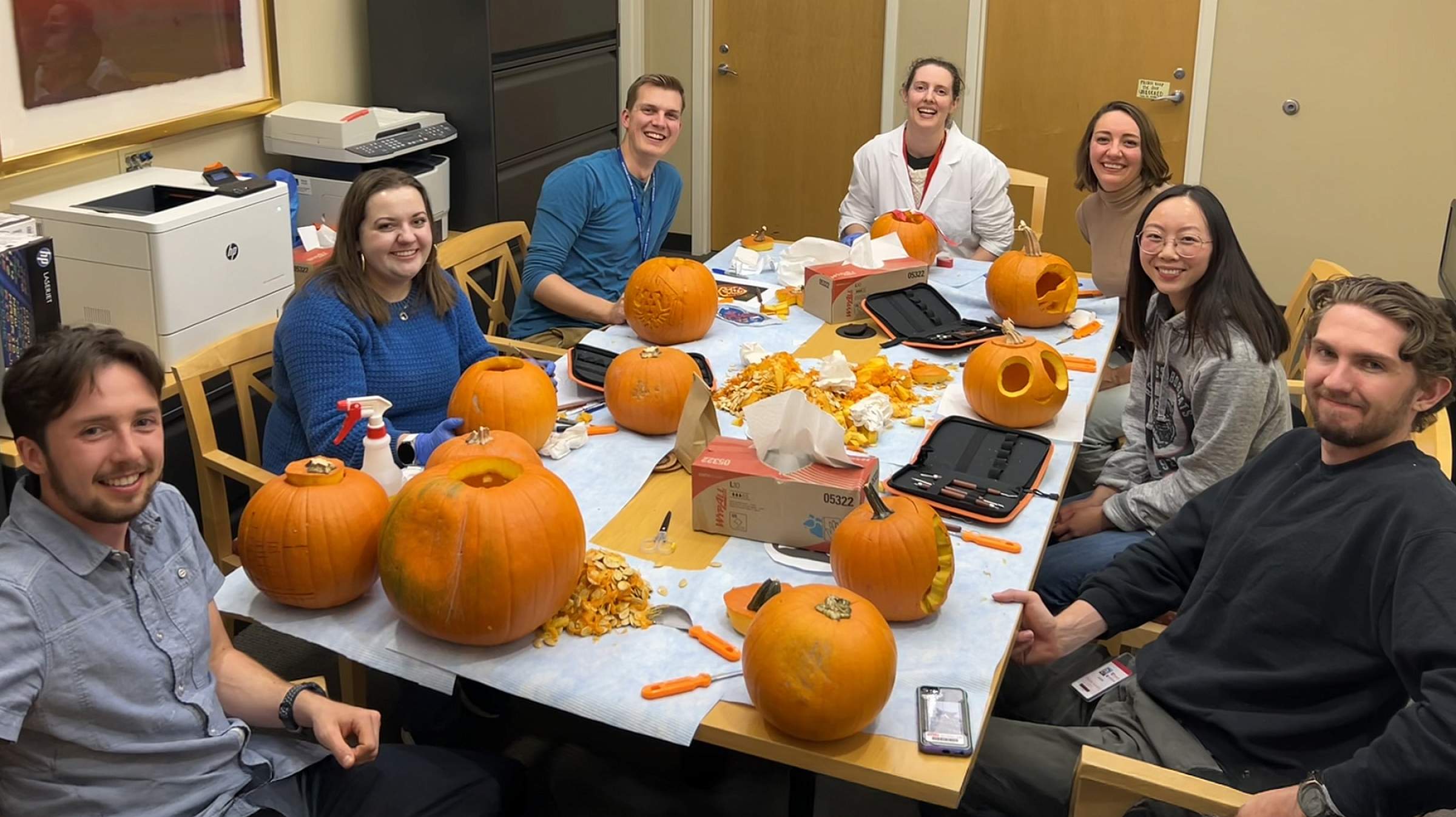 Members of the Young Lab around a table carving pumpkins